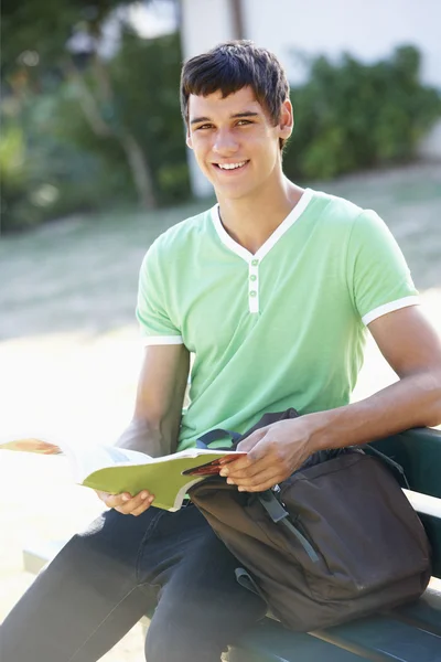 Étudiant assis sur un banc avec livre — Photo