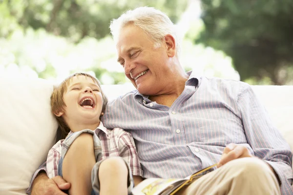 Děda s vnukem čtení na pohovce — Stock fotografie