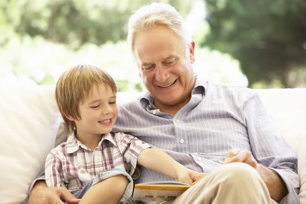 Grand-père avec petit-fils lisant sur le canapé — Photo