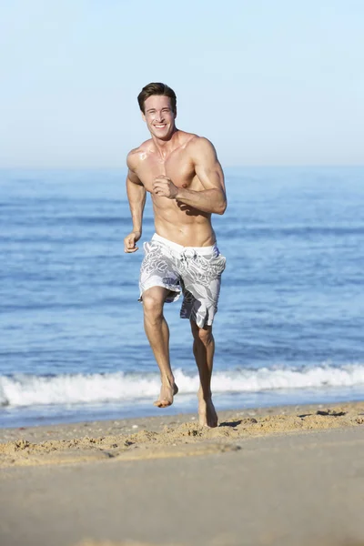 Człowiek biegnie wzdłuż plaży — Zdjęcie stockowe