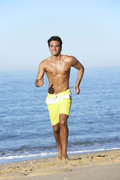 Muž běží podél pláže — Stock fotografie