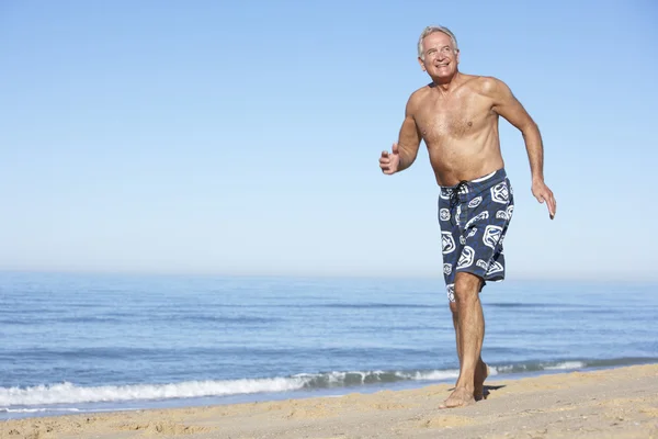 Senior Man loopt langs strand — Stockfoto