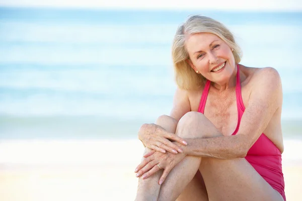 Senior vrouw zittend op strand — Stockfoto