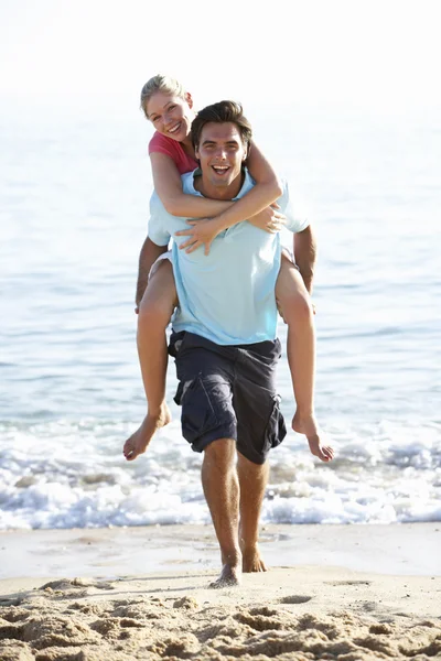 Paar genieten van meeliften op strand — Stockfoto