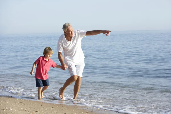 Grand-père et petit-fils marchant le long de la plage — Photo