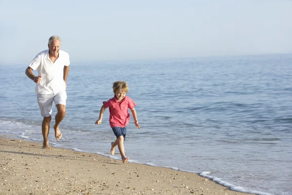Abuelo y nieto corriendo por la playa — Foto de Stock