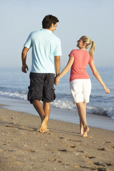 Jeune couple marchant le long de la plage — Photo