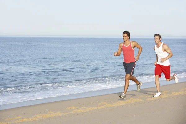 Männer joggen am Strand entlang — Stockfoto