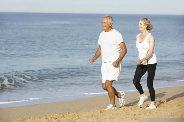 Couple sénior jogging le long de la plage — Photo