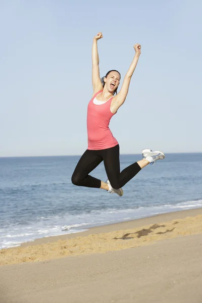 Frau springt am Strand in die Luft — Stockfoto