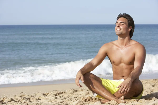 Unge man sitter på stranden — Stockfoto