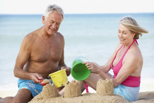 Idősebb pár Sandcastles, hogy a strandon — Stock Fotó
