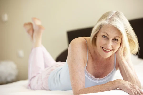 Старшая женщина отдыхает на кровати — стоковое фото