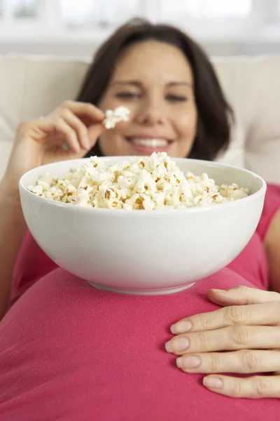 Беременная женщина ест попкорн — стоковое фото