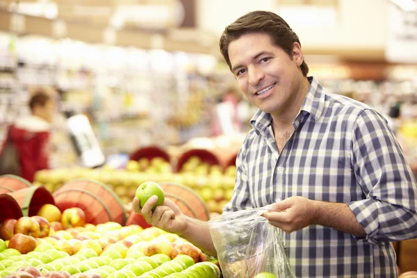 Чоловік купує фрукти в супермаркеті — стокове фото
