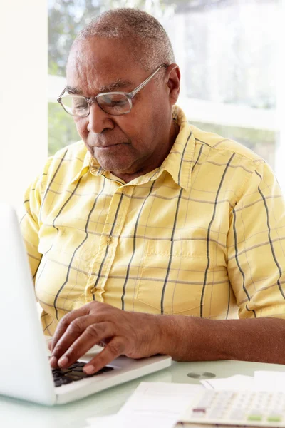 Пожилой мужчина пользуется ноутбуком дома — стоковое фото