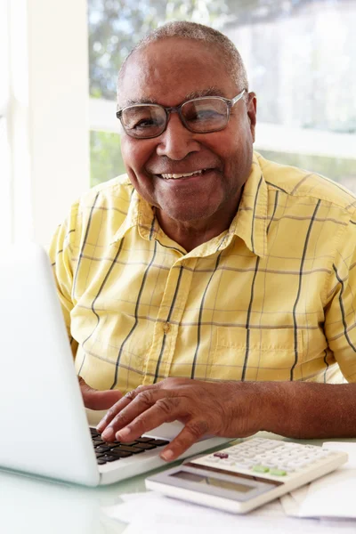 Homem sênior usando laptop em casa — Fotografia de Stock