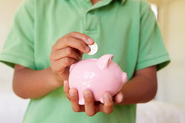 Pojken att lägga pengar i piggybank — Stockfoto