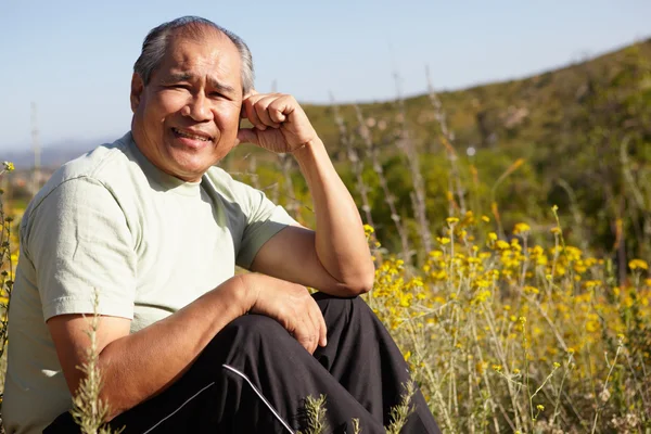 Hombre mayor sentado en el campo — Foto de Stock