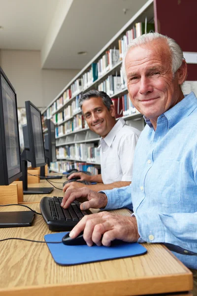 Mannen die werken op computers in de bibliotheek — Stockfoto