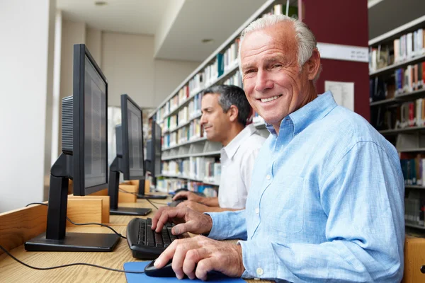 Men working on computers in library — Stock Photo, Image