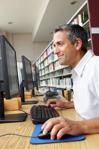 Man som arbetar på dator i biblioteket — Stockfoto