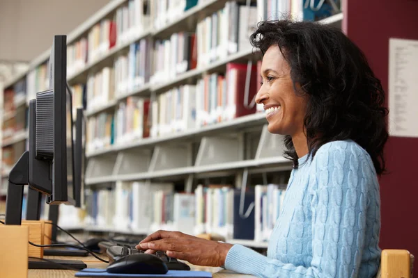 Vrouw die op de computer in de bibliotheek werkt — Stockfoto