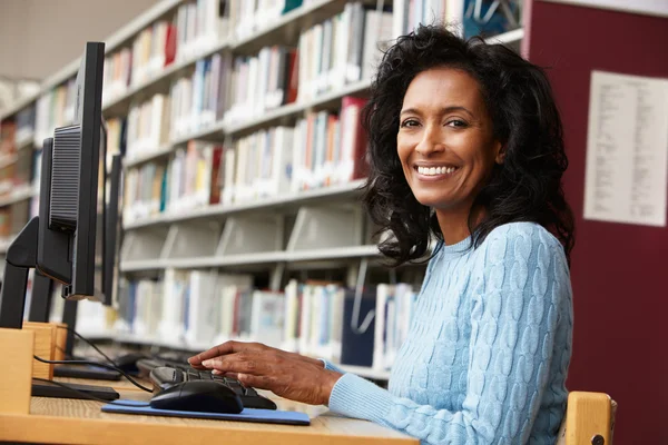 Kvinna som arbetar på dator i biblioteket — Stockfoto