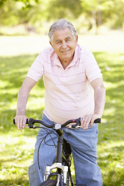 Senior man fietsen in park — Stockfoto