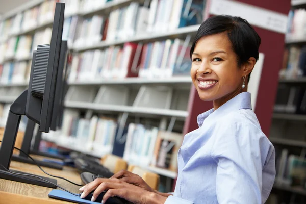 Vrouw die op de computer in de bibliotheek werkt — Stockfoto