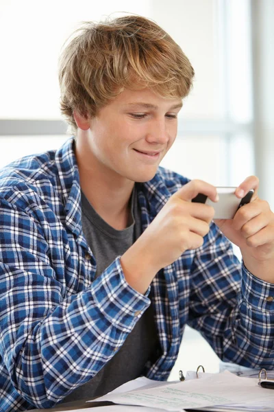 Adolescent garçon avec téléphone portable en classe — Photo