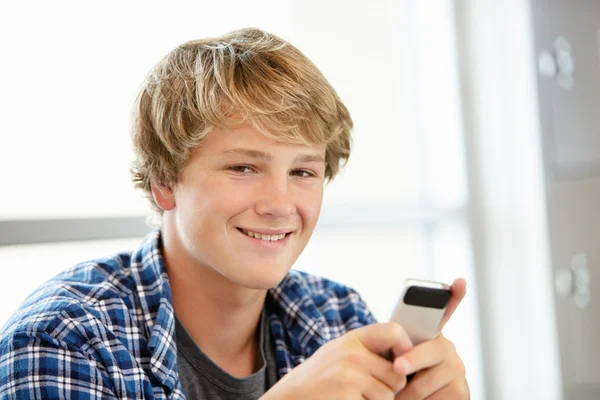 Teenage boy with mobile phone in class — Stockfoto