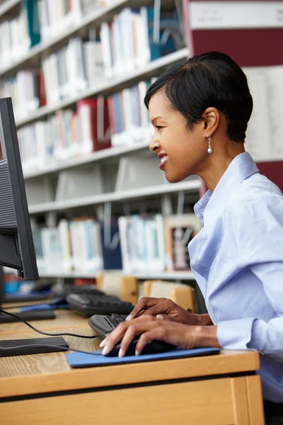 Женщина, работающая на компьютере в библиотеке — стоковое фото