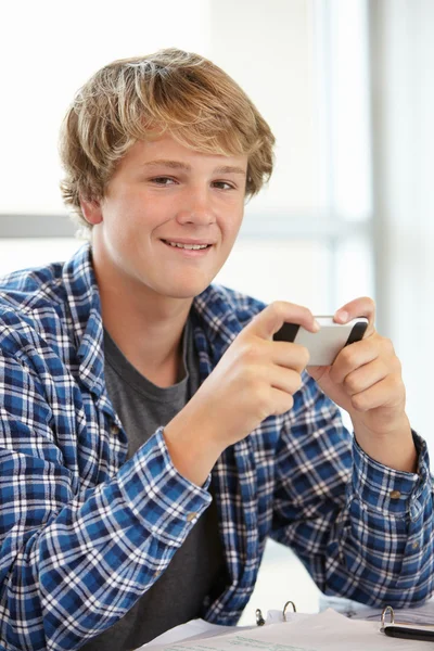 Teenage boy with mobile phone in class — Stockfoto