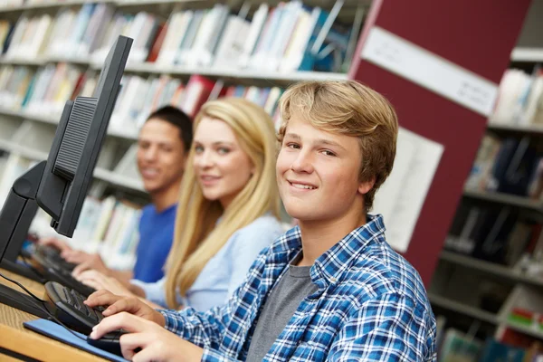 Teenagers working on computers in library — Stockfoto