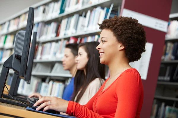 Adolescentes trabalhando em computadores na biblioteca — Fotografia de Stock