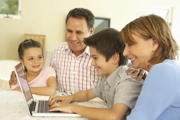 Großeltern und Enkel nutzen Computer zu Hause — Stockfoto