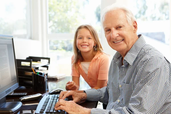 Senior man en kleindochter met behulp van computer — Stockfoto