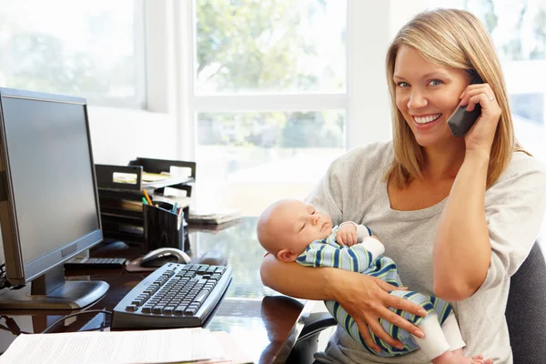 Mother working with baby in home office