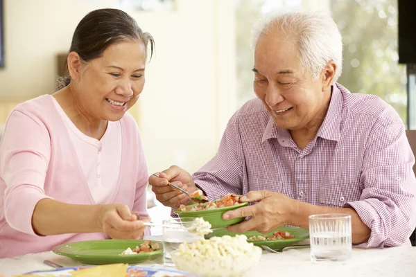 Старша пара ділиться їжею вдома — стокове фото