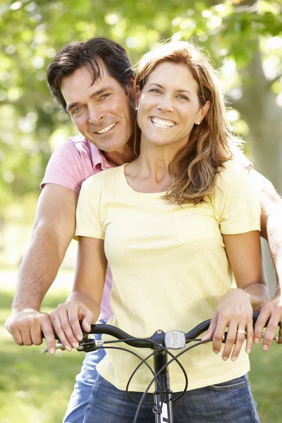 Happy couple using bike in park — Stock fotografie