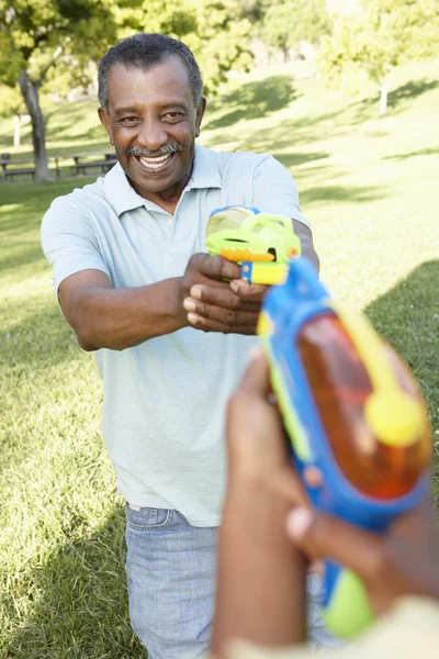 Farfar och barnbarn leker med vatten pistoler — Stockfoto