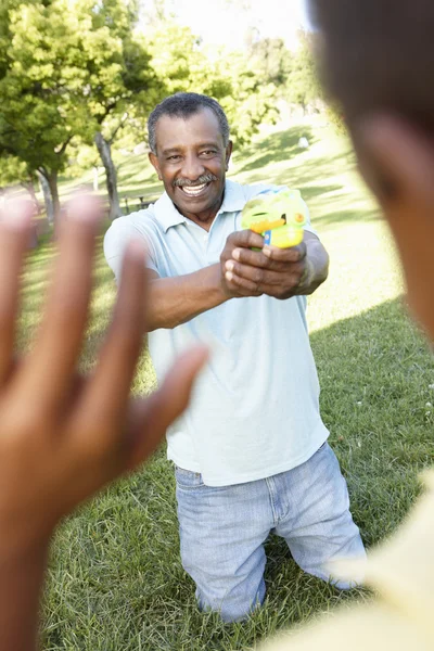 Avô e neto brincando com pistolas de água — Fotografia de Stock