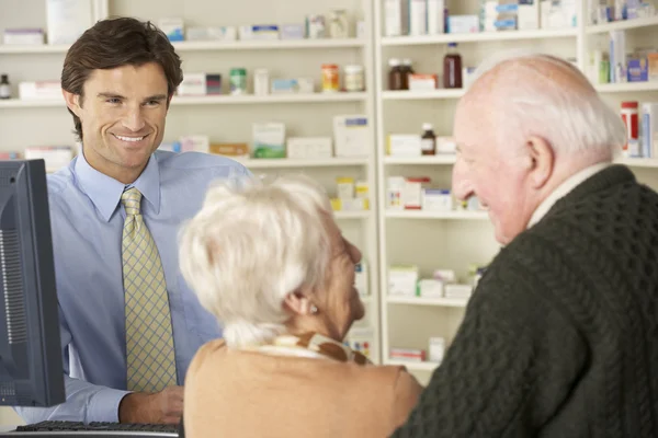 Farmacista con coppia anziana in farmacia — Foto Stock