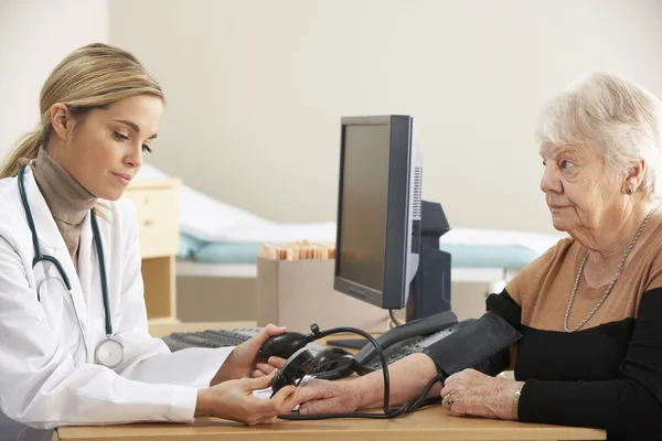 Médico tomando la presión arterial de la mujer —  Fotos de Stock