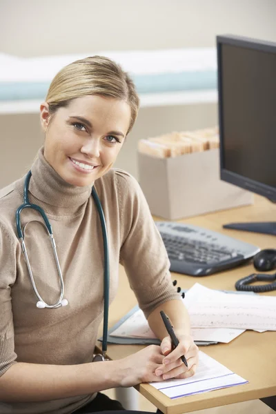 Vrouwelijke arts zit aan Bureau — Stockfoto