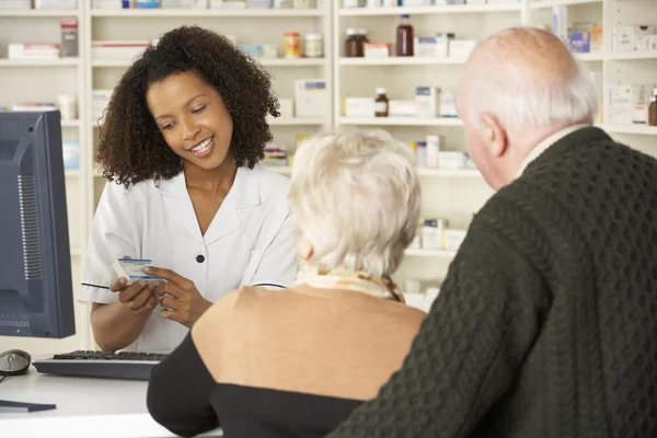 Farmacéutica con pareja mayor en farmacia — Foto de Stock