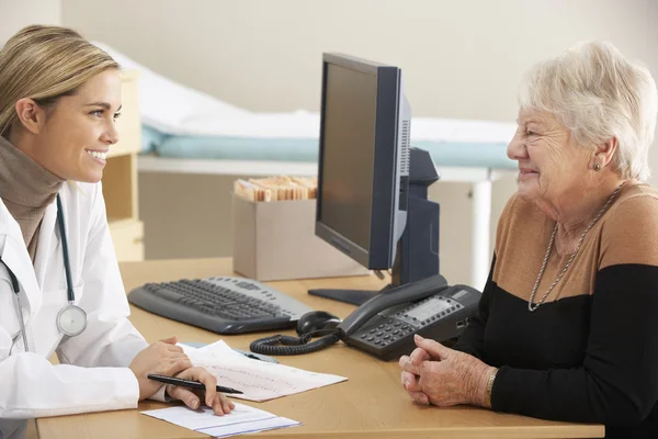 Läkare pratar med äldre kvinna — Stockfoto