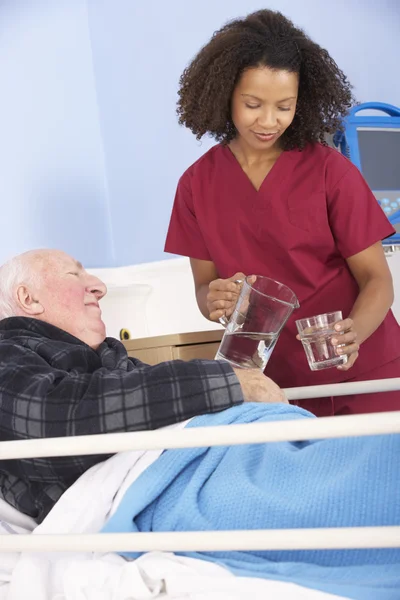 Verpleegkundige glas water geven aan de mens — Stockfoto