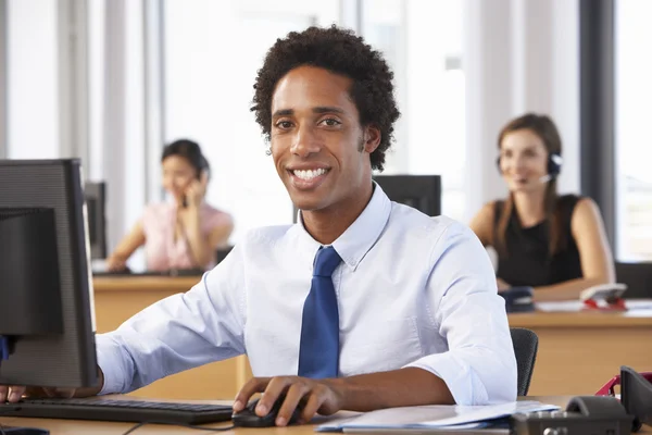 Trabalhador sorridente no escritório ocupado — Fotografia de Stock